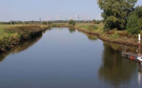 Blick auf die Ochtum in Bremen Strom, an einem Steg liegt ein Boot, blauer Himmel
